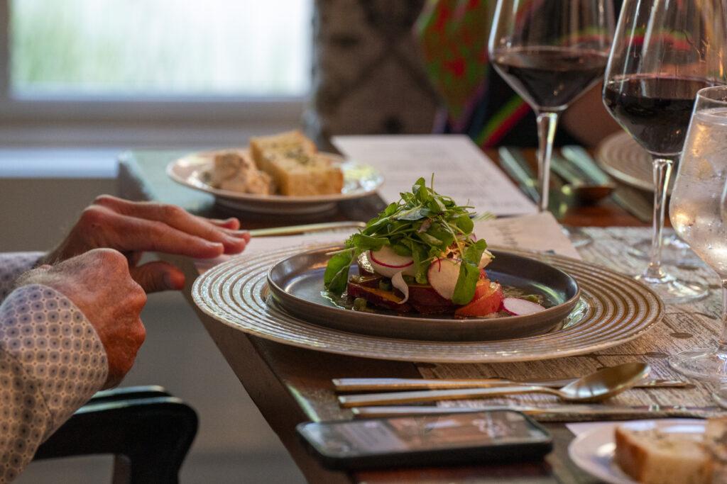 Place setting with Burrata Salad with Charred English Peas and Glass of Wine