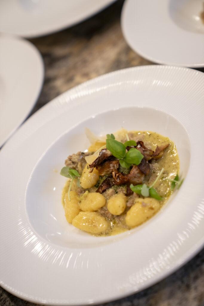 Gnocchi with Rock Shrimp and Italian Sausage, served with Calabrian chili lobster, blistered tomatoes, crispy artichokes, capers, lemon, and parsley