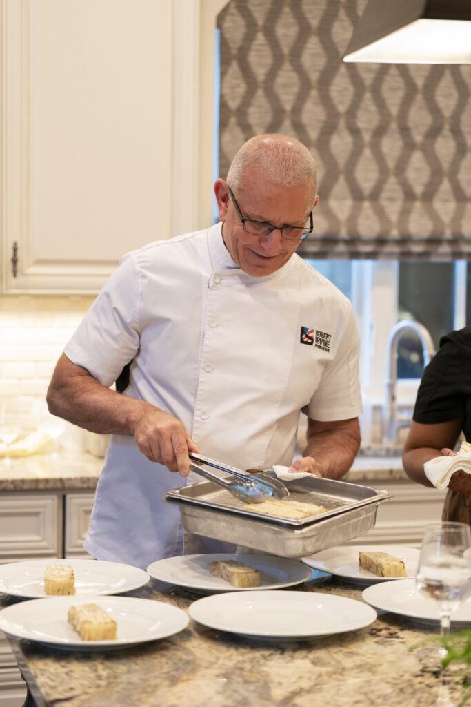 Chef Robert Irvine plating a meal at a private residence